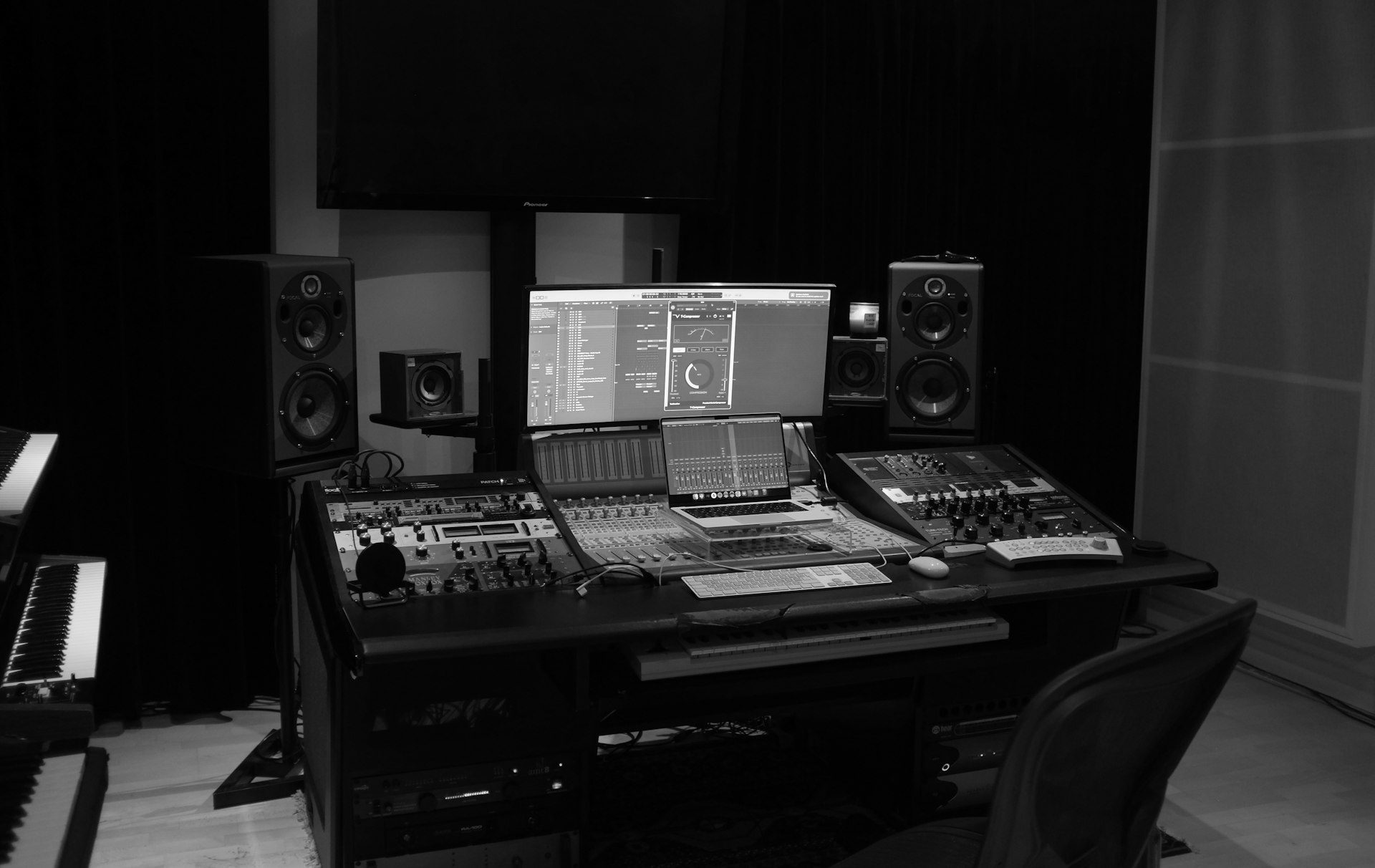Mesa de producción con monitores, teclados y consola
